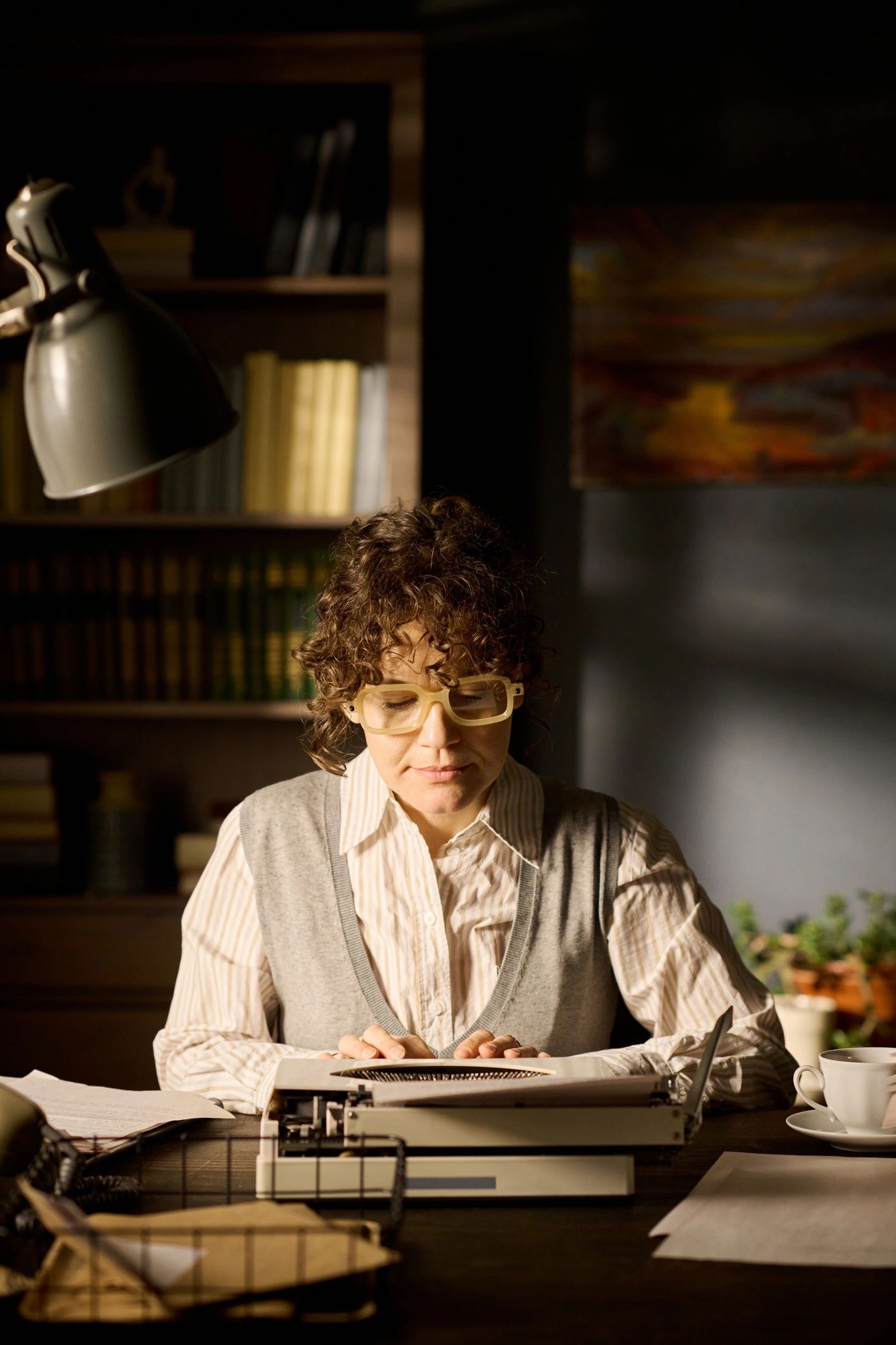 Writer using a typewriter in a book-lined room